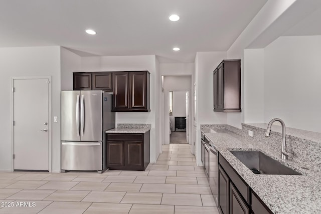 7086 W Spur Dr, Peoria, AZ 85383 - kitchen featuring appliances with stainless steel finishes, light stone countertops, dark brown cabinetry, and recessed lighting
