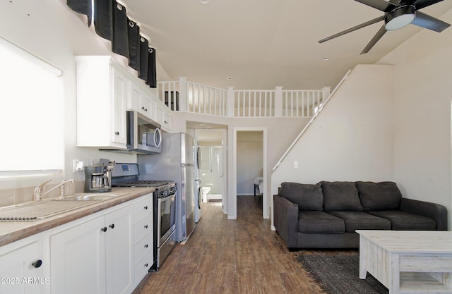 kitchen with a sink, white cabinetry, stainless steel appliances, ceiling fan, and dark wood-type flooring