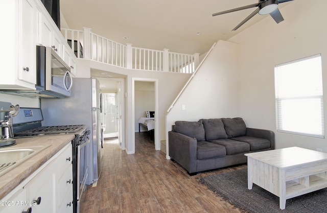 living room featuring ceiling fan, stairway, and dark wood finished floors