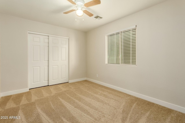 unfurnished bedroom with ceiling fan, a closet, and light colored carpet