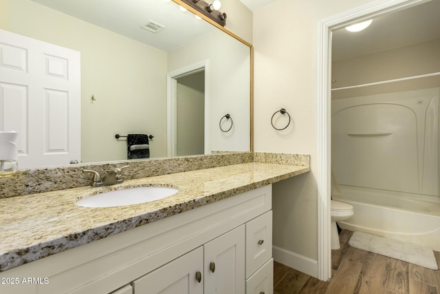 full bathroom featuring washtub / shower combination, toilet, wood-type flooring, and vanity