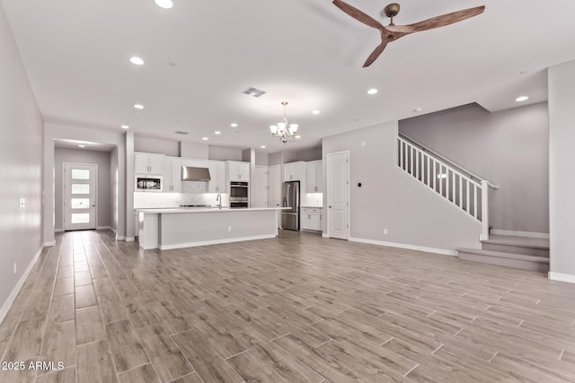 7492 E Via De Luna Dr, Scottsdale, AZ 85255 - unfurnished living room with stairway, light wood-style flooring, a ceiling fan, recessed lighting, and a chandelier