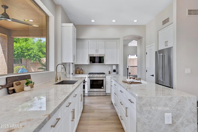 3624 N Paseo Del Sol, Mesa, AZ 85207 - kitchen with appliances with stainless steel finishes, a sink, arched walkways, a center island, and plenty of natural light
