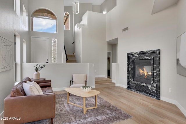 3624 N Paseo Del Sol, Mesa, AZ 85207 - living room featuring a high ceiling, stairs, wood finished floors, a premium fireplace, and baseboards