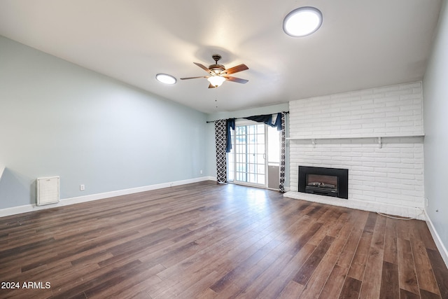 unfurnished living room featuring dark hardwood / wood-style floors, ceiling fan, and a brick fireplace