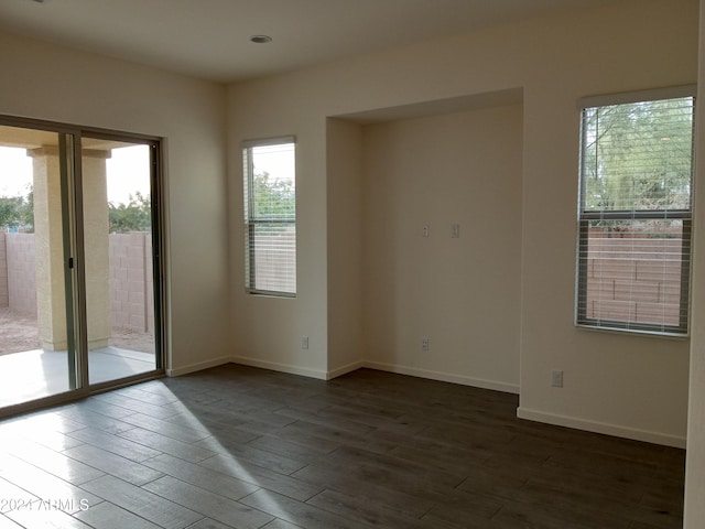 unfurnished room featuring a healthy amount of sunlight and dark wood-type flooring