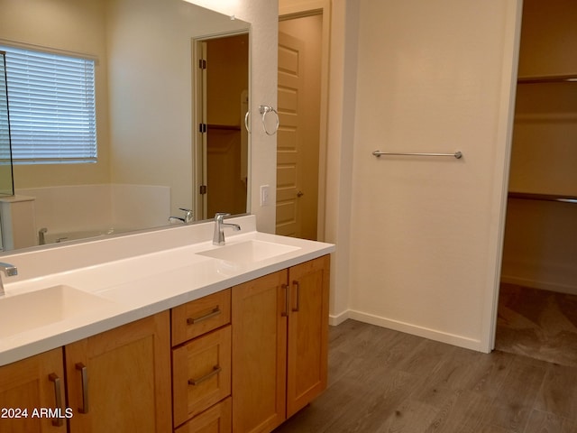 bathroom with wood-type flooring, vanity, and a tub