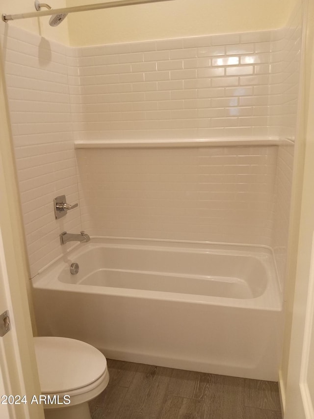 bathroom featuring hardwood / wood-style floors, tiled shower / bath combo, and toilet