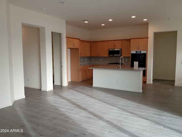 kitchen featuring decorative backsplash, a center island with sink, light hardwood / wood-style floors, and sink