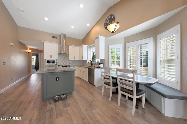 26647 N 43rd St N, Cave Creek, AZ 85331 - kitchen with wall chimney range hood, stainless steel appliances, white cabinetry, a center island, and light wood-style floors