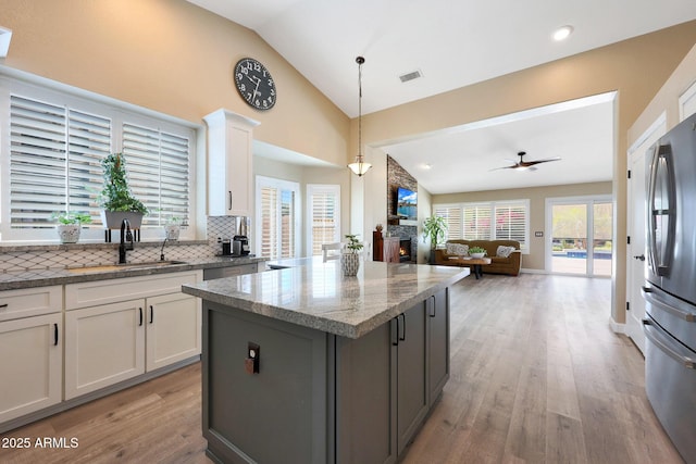 26647 N 43rd St N, Cave Creek, AZ 85331 - kitchen with lofted ceiling, freestanding refrigerator, a fireplace, light wood finished floors, and decorative backsplash