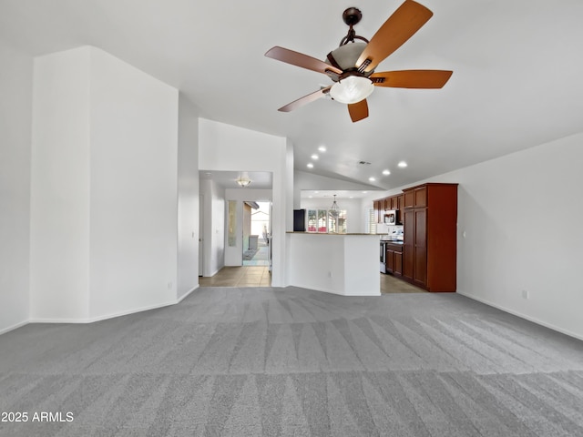 unfurnished living room with ceiling fan with notable chandelier, light carpet, and vaulted ceiling