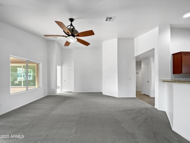 unfurnished living room featuring ceiling fan and carpet