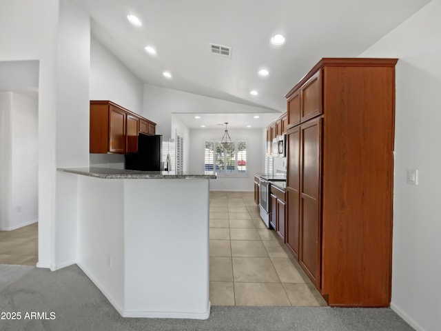 kitchen featuring pendant lighting, vaulted ceiling, light tile patterned floors, kitchen peninsula, and stainless steel appliances