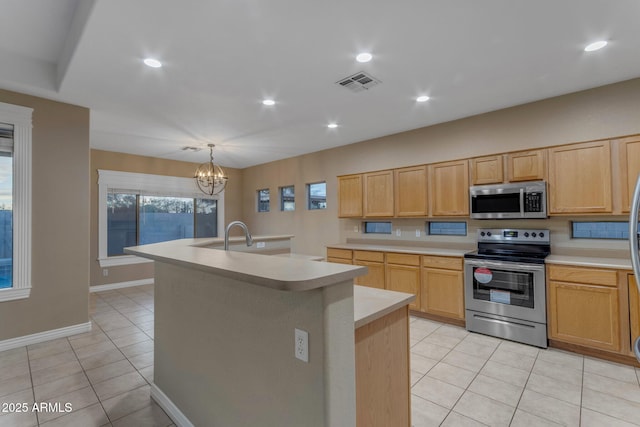 kitchen with appliances with stainless steel finishes, a kitchen island with sink, light tile patterned floors, and light brown cabinetry