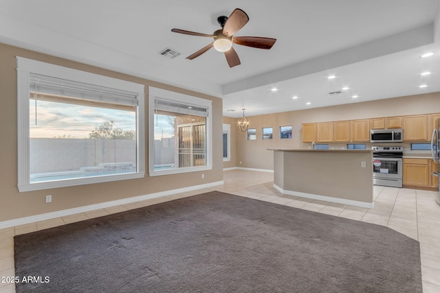 kitchen featuring light brown cabinetry, light tile patterned floors, pendant lighting, stainless steel appliances, and ceiling fan with notable chandelier