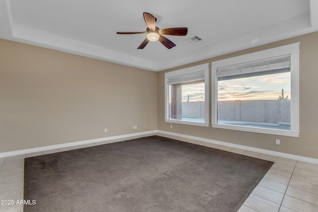 spare room featuring light tile patterned floors, ceiling fan, and a tray ceiling