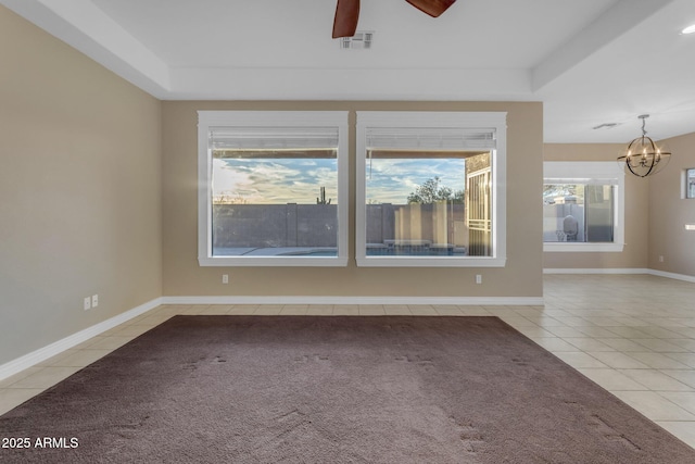 tiled spare room with a tray ceiling and ceiling fan with notable chandelier