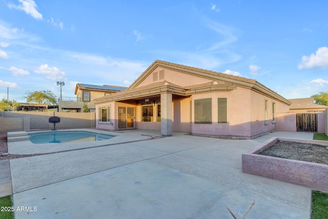 back of property featuring a fenced in pool and a patio area