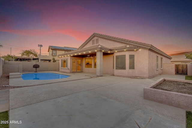 pool at dusk featuring a patio