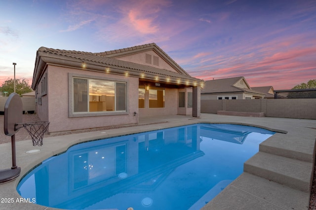 pool at dusk featuring a patio area