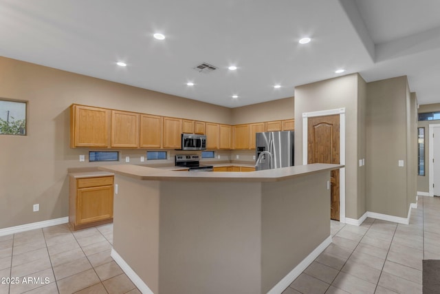 kitchen featuring appliances with stainless steel finishes, light brown cabinetry, an island with sink, and light tile patterned floors