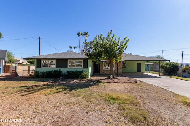 single story home with an attached carport, roof with shingles, driveway, and fence