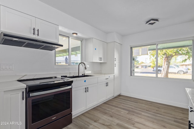 kitchen with white cabinets, light wood-type flooring, electric range, and sink