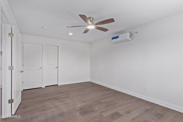 unfurnished room featuring a wall mounted air conditioner, hardwood / wood-style floors, and ceiling fan