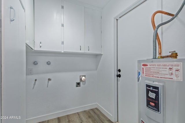 clothes washing area with cabinets, electric water heater, and light hardwood / wood-style flooring