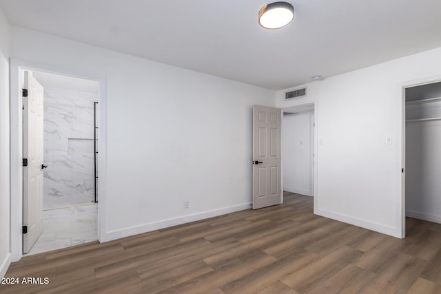 unfurnished bedroom with wood finished floors, baseboards, and visible vents