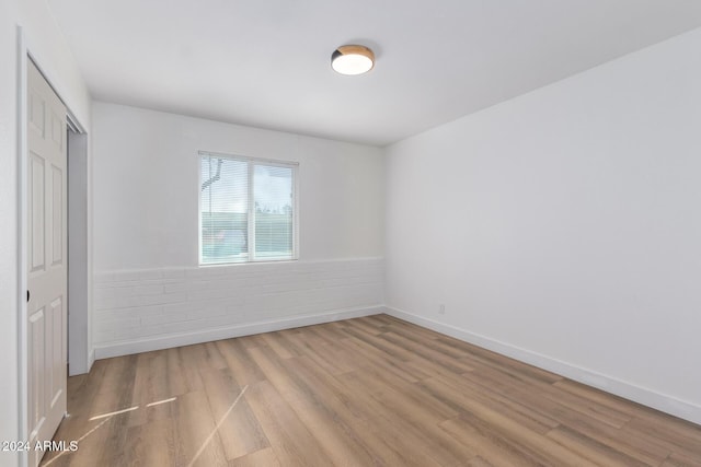 unfurnished room featuring a wainscoted wall, baseboards, and wood finished floors