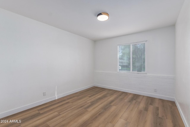 empty room with a wainscoted wall, baseboards, and wood finished floors