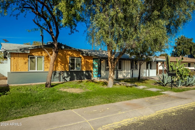 ranch-style house featuring concrete block siding and a front yard