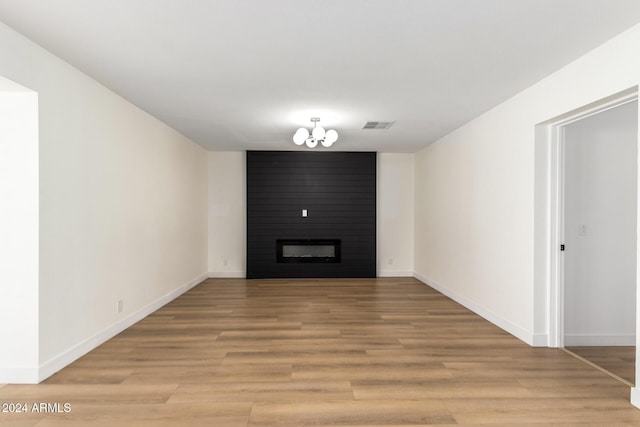 unfurnished living room with a notable chandelier, light wood-style floors, visible vents, and baseboards