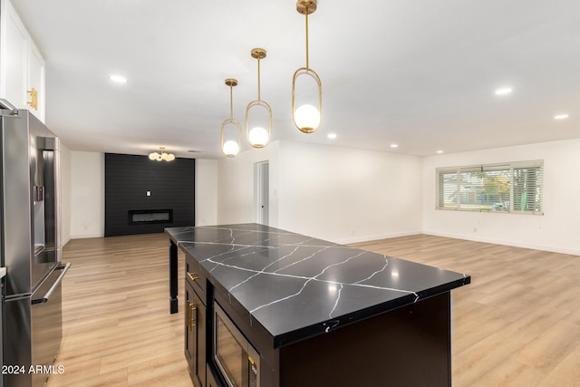 kitchen with dark countertops, light wood finished floors, open floor plan, a fireplace, and stainless steel appliances