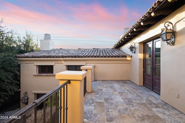 balcony at dusk featuring a patio