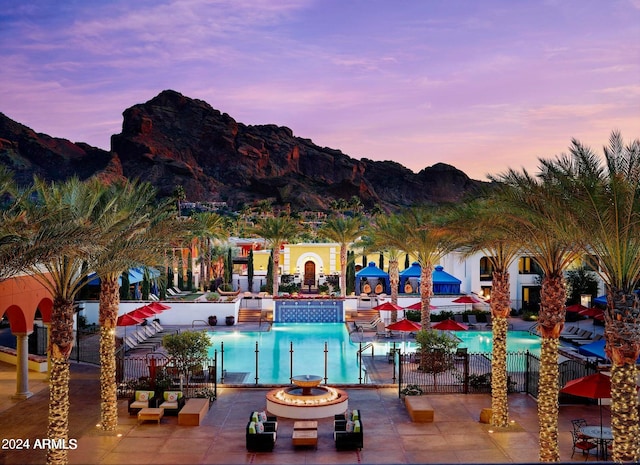 pool at dusk with a patio and a mountain view