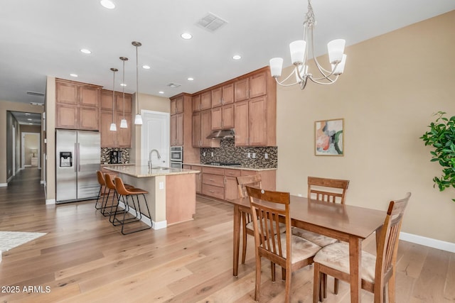 7630 E Knoll St, Mesa, AZ 85207 - kitchen featuring stainless steel appliances, tasteful backsplash, visible vents, under cabinet range hood, and a kitchen breakfast bar