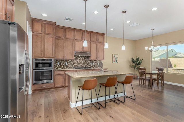 7630 E Knoll St, Mesa, AZ 85207 - kitchen featuring under cabinet range hood, a sink, light wood-style floors, appliances with stainless steel finishes, and decorative backsplash