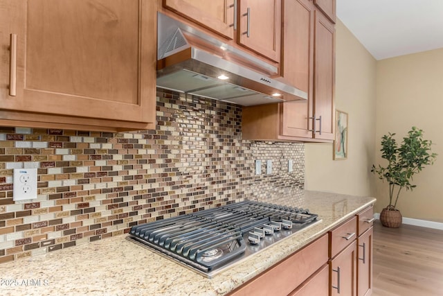 7630 E Knoll St, Mesa, AZ 85207 - kitchen featuring light stone counters, under cabinet range hood, decorative backsplash, light wood finished floors, and stainless steel gas stovetop