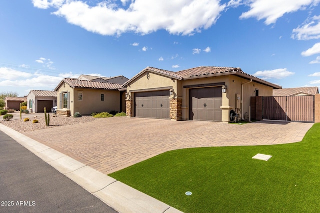 view of front of home featuring a garage, a tile roof, decorative driveway, a gate, and stucco siding