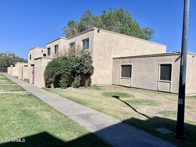 view of home's exterior featuring fence, a lawn, and stucco siding