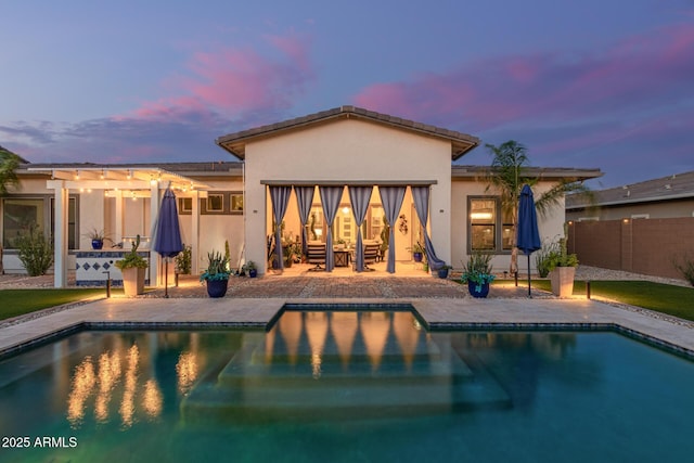 5218 N Tiller Dr, Litchfield Park, AZ 85340 - back of property at dusk with stucco siding, an outdoor pool, and a patio