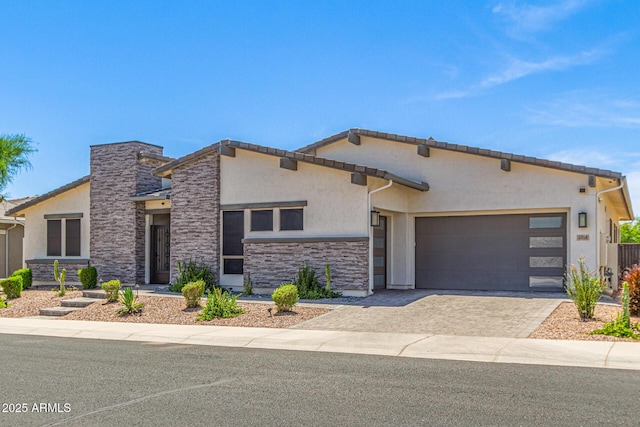 5218 N Tiller Dr, Litchfield Park, AZ 85340 - view of front of house with stucco siding, an attached garage, stone siding, and decorative driveway