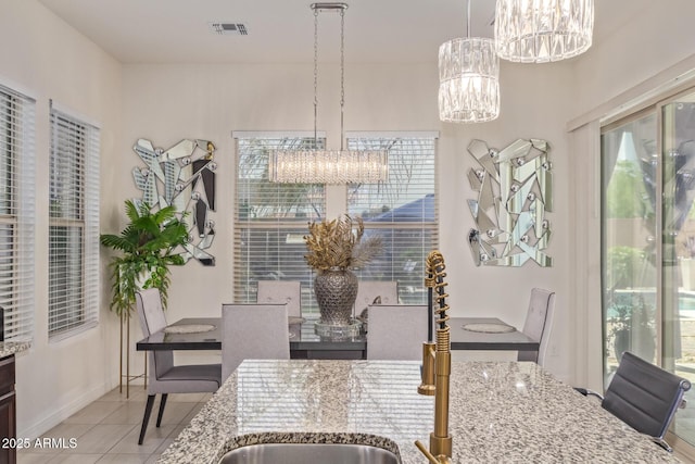 5218 N Tiller Dr, Litchfield Park, AZ 85340 - dining space featuring a chandelier, healthy amount of natural light, light tile patterned floors, and baseboards