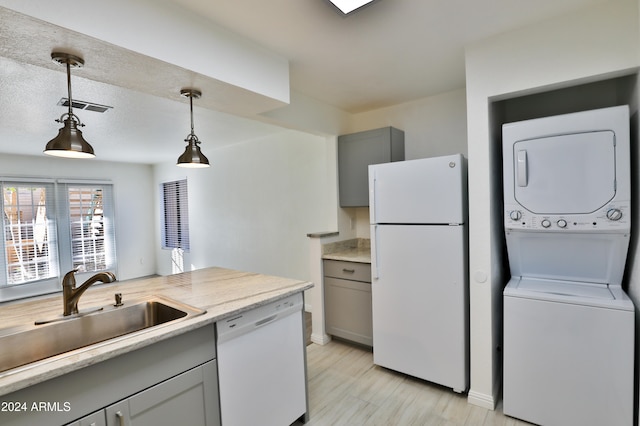 kitchen with gray cabinets, pendant lighting, stacked washing maching and dryer, and white appliances