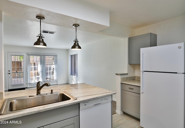 kitchen featuring light stone counters, gray cabinetry, white appliances, sink, and pendant lighting