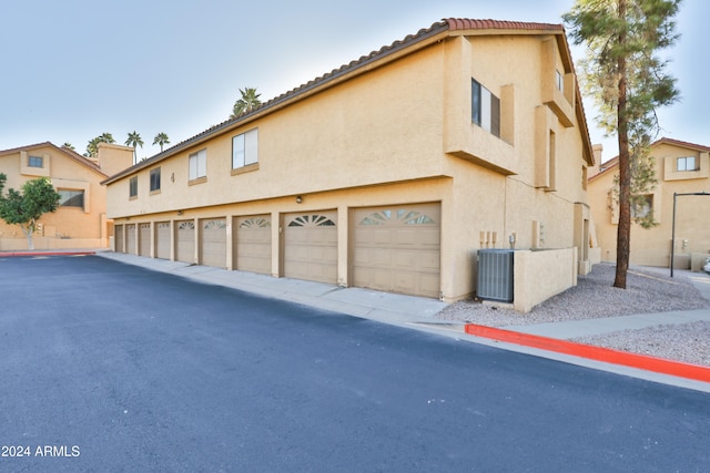 view of side of home with a garage and central AC