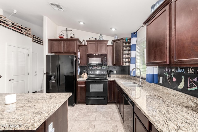 kitchen featuring lofted ceiling, sink, tasteful backsplash, light stone countertops, and black appliances